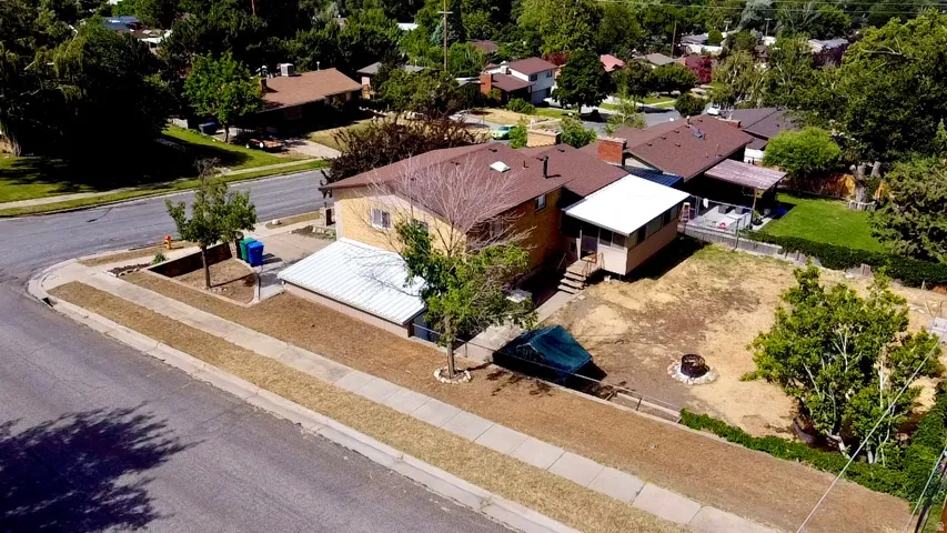 Corner lot property featuring a covered patio, extensive backyard space, and mature trees