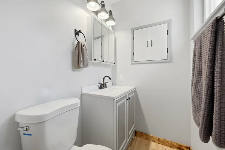 Bathroom featuring a white toilet, light gray vanity with white countertop, and a built-in medicine cabinet with a mirror