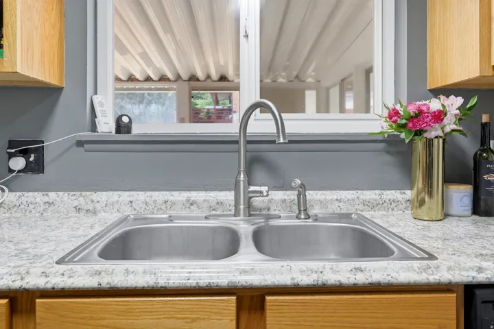 Double basin stainless steel sink with a high-arc faucet, set within a speckled countertop