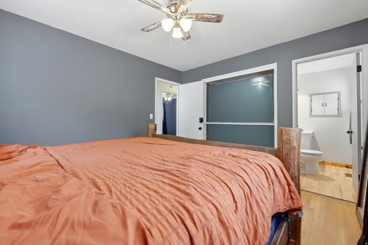 Bedroom featuring a ceiling fan, grey wall paint, and wood-finish flooring