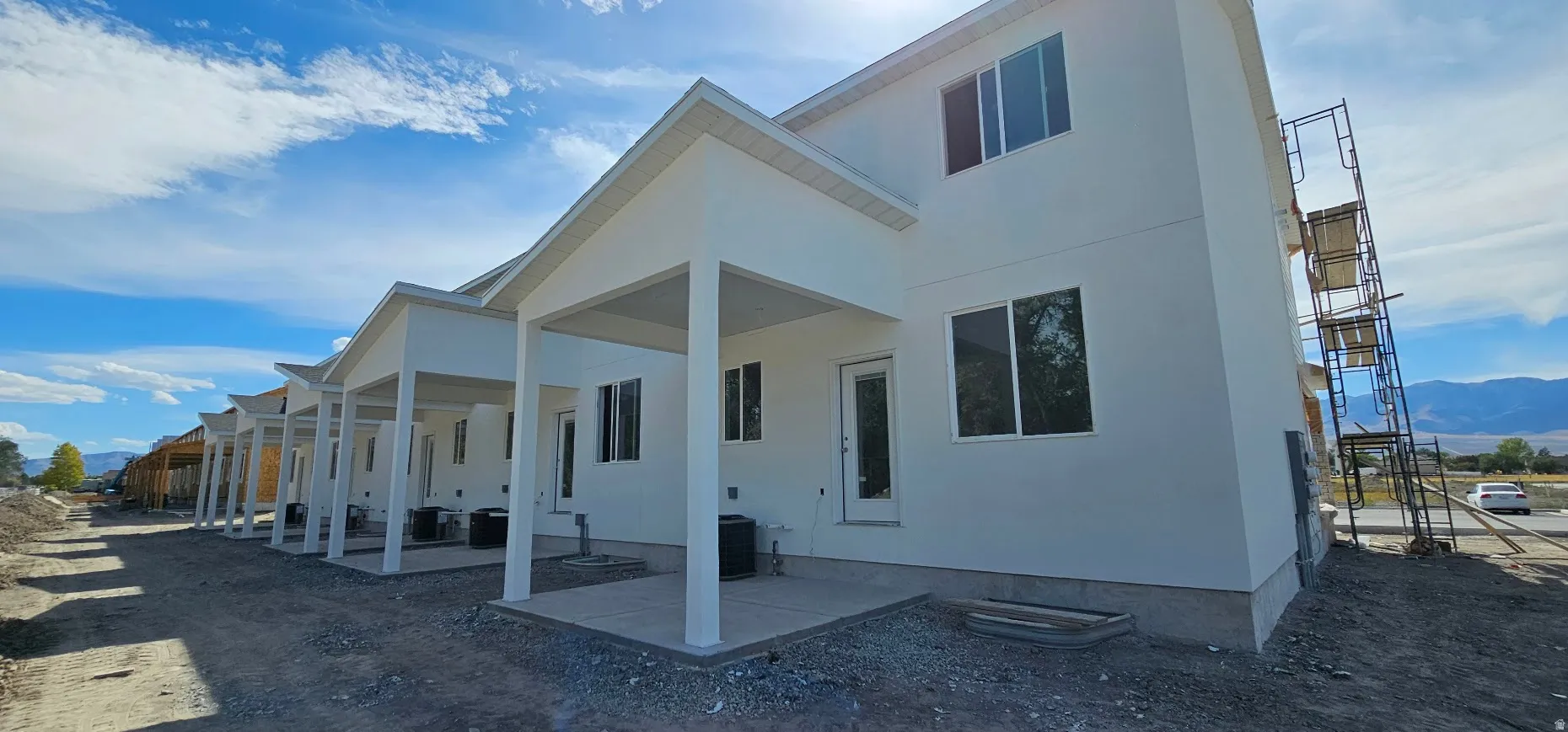 Multiple units featuring white exterior finishes, covered patios, and individual outdoor HVAC units