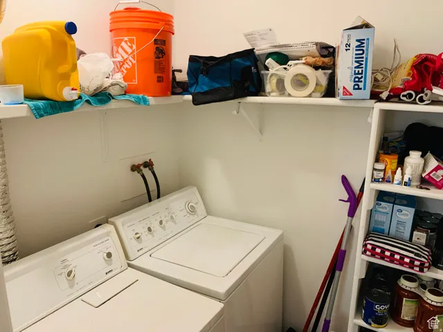 White top-load washer and dryer pair with wall-mounted utility connections