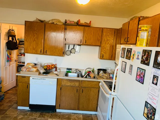 Kitchen featuring wood-finish cabinetry, laminate countertops, and a white dishwasher