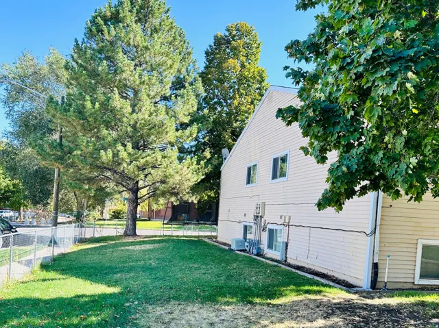 Side yard featuring a chain-link fence, mature trees, and a manicured lawn