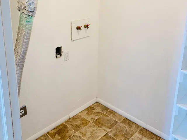 Dedicated laundry area featuring a patterned vinyl floor, utility hookups, and built-in shelving