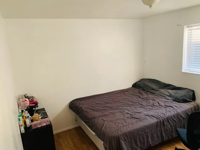 Room featuring wood-finish flooring, a window with horizontal blinds, and a flush-mount ceiling fixture