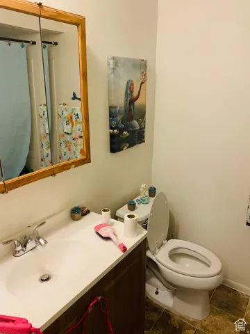 Bathroom featuring a wood-frame vanity mirror, single-basin vanity with a laminate countertop, and a white porcelain toilet