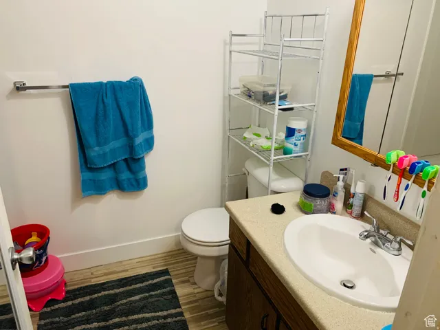 Bathroom featuring a single vanity with laminate countertop, wood-finish cabinetry, and a framed mirror
