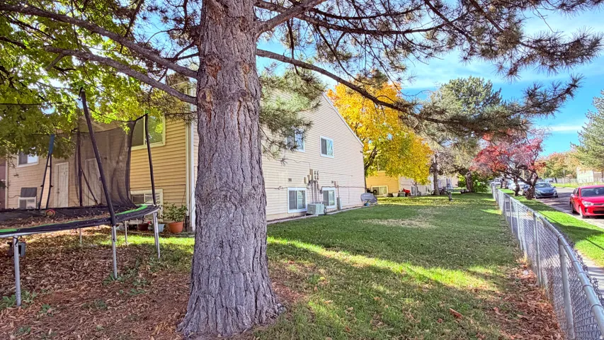 Expansive green space featuring mature trees and a chain-link fence