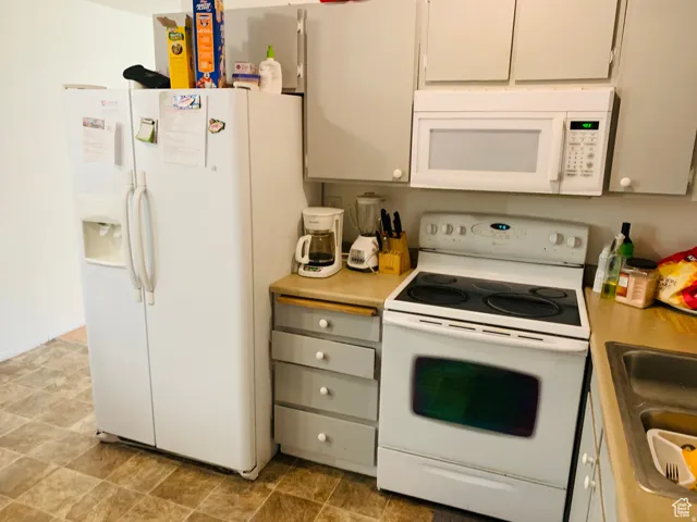Kitchen space with white appliances, including a side-by-side refrigerator with water/ice dispenser, an electric range, and an over-the-range microwave