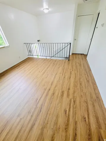Spacious interior with wood-finish flooring, crisp white walls, and a recessed ceiling light