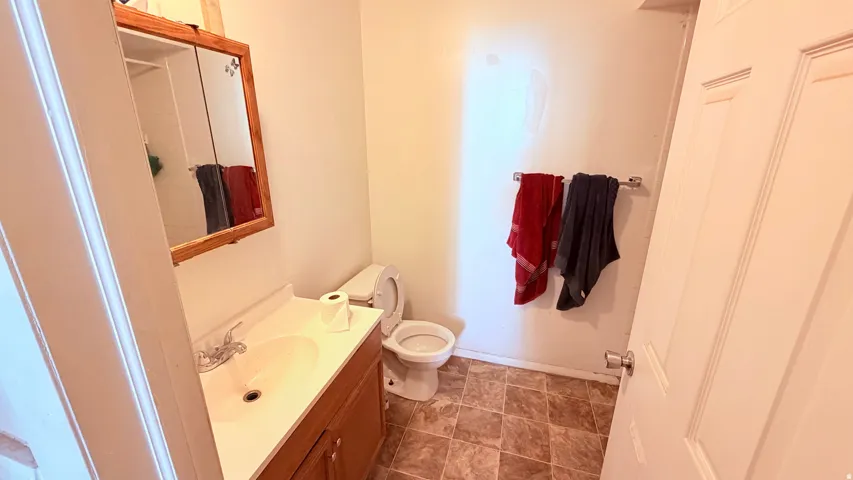 Bathroom featuring a wood-finish vanity with an integrated sink, a matching wood-frame mirrored medicine cabinet, and a toilet