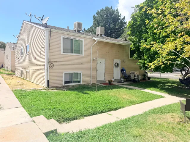 Beige siding exterior with multiple windows and a mature tree