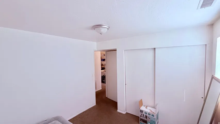 Bedroom featuring neutral wall paint, carpet flooring, a flush-mount ceiling light fixture, and sliding closet doors
