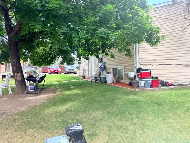 Expansive grassy yard area featuring a mature shade tree and established landscaping beds