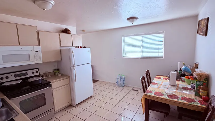 Kitchen featuring white appliances, upper and lower cabinetry, a stainless steel range, and tile flooring