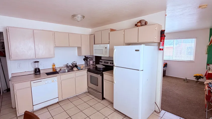 Functional kitchen featuring light-toned cabinetry, laminate countertops, a stainless steel range, and a white dishwasher
