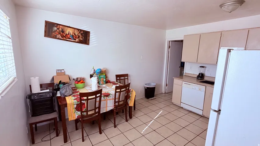 Kitchen area featuring light beige cabinetry, white appliances, and tiled flooring