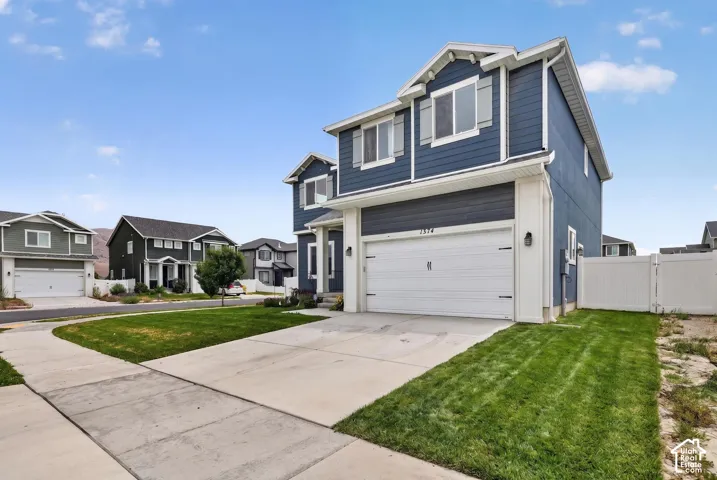 Two-story home featuring a blue siding exterior with white trim, a two-car garage, and a concrete driveway