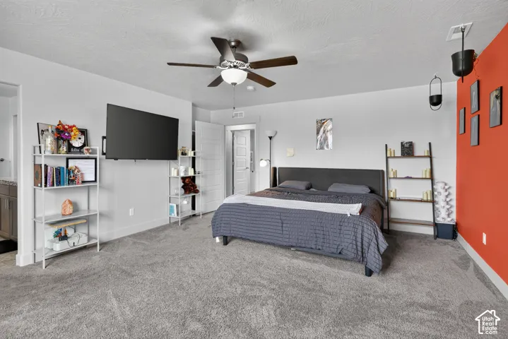 Spacious room featuring neutral carpeting, a ceiling fan with integrated lighting, and a vibrant accent wall