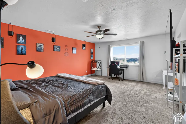 Spacious room featuring carpeting, a ceiling fan with integrated lighting, and a large window