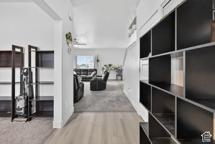 Hallway featuring light wood-finish flooring, white walls, and a built-in shelving unit with black-finished cubbies