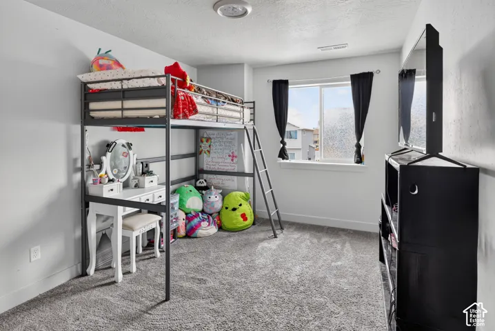 Carpeted room featuring a double window with black curtains, white baseboards, and neutral wall tones