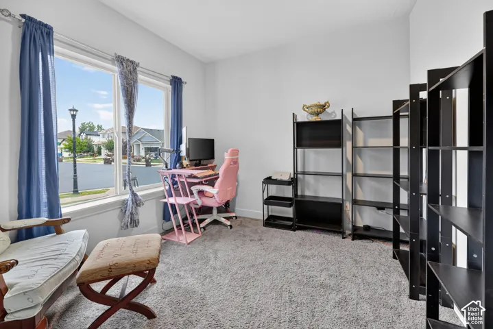 Room with light gray walls, gray carpet flooring, and a large window