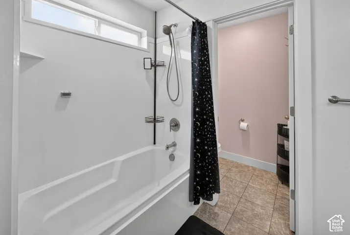 Bathtub and shower combination featuring a white surround, overhead transom window, and brushed nickel fixtures