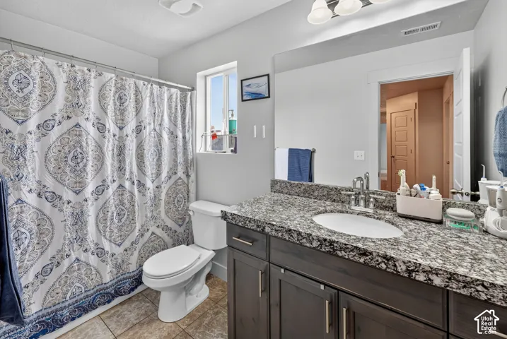 Bathroom featuring a dark wood vanity with a granite countertop, an undermount sink, and a large mirror