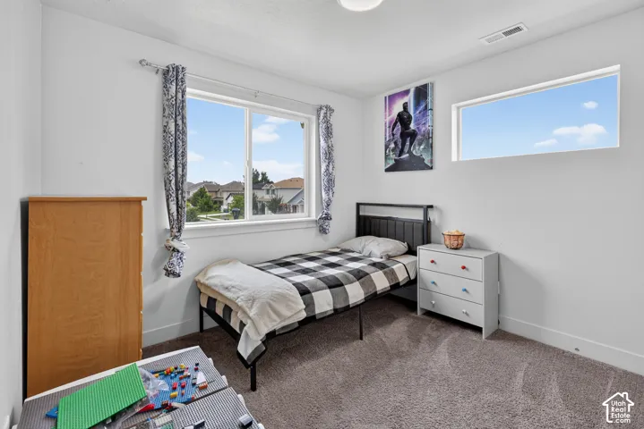 Bedroom featuring light neutral wall paint, carpet flooring, a large window, a high horizontal window, and white baseboards