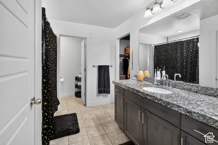 Bathroom featuring a spacious vanity with a speckled countertop, a rectangular undermount sink, and brushed nickel fixtures