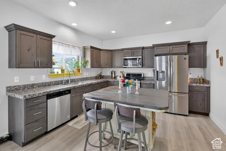 Kitchen featuring wood-finish cabinetry, speckled countertops, stainless steel appliances, and wood-finish flooring
