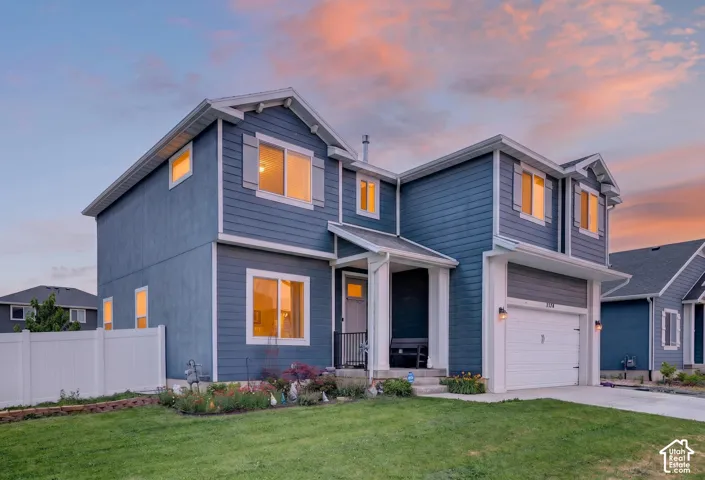 Contemporary residential exterior featuring blue siding with white trim, a two-car garage, and a manicured front lawn