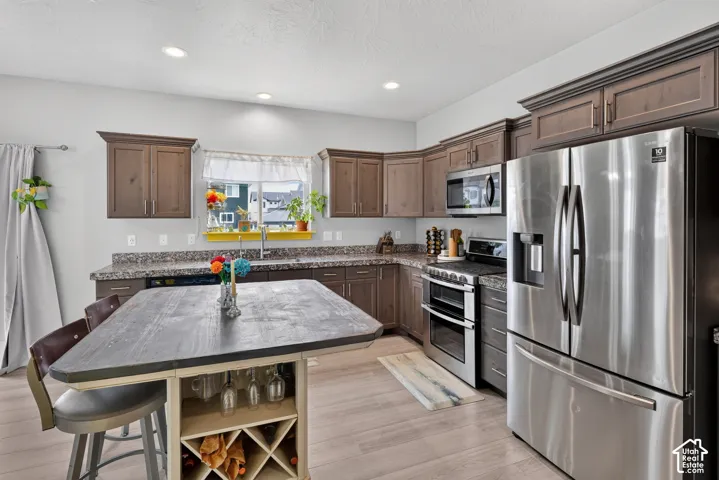 Modern kitchen featuring wood-finish flooring, recessed lighting, and dark wood cabinetry