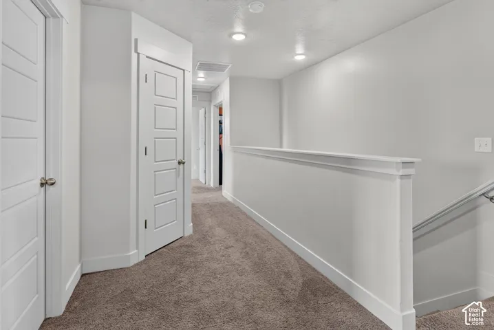 Upper-level hallway with neutral carpeting, white trim, and recessed ceiling lighting