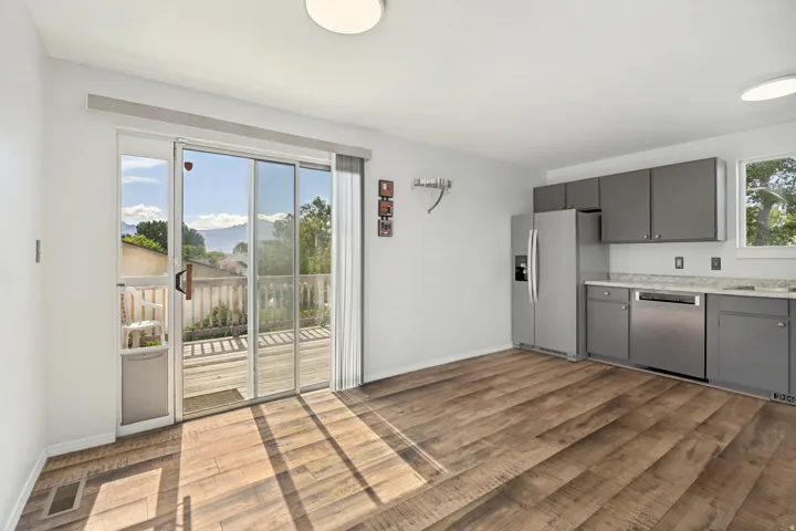 Open concept room featuring wood-finish flooring, a kitchen area with gray cabinetry, stainless steel appliances, and light-toned countertops