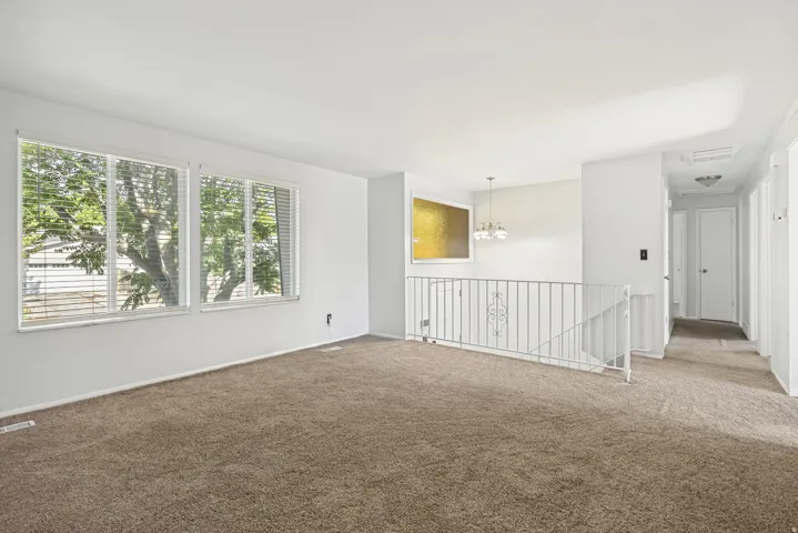 Light-filled interior featuring two large windows with horizontal blinds and a neutral carpeted floor