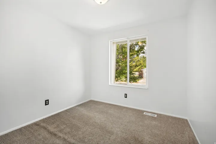 Room featuring neutral carpeting, white walls, and a window providing natural illumination