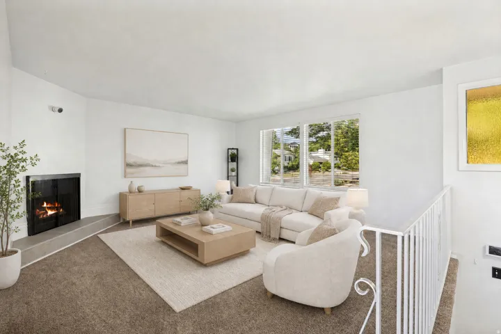 Spacious living area featuring a corner fireplace with a dark metal screen and a raised hearth