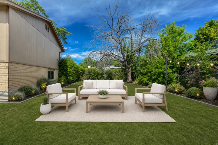 Expansive backyard featuring a manicured lawn, established perimeter greenery, and string lighting