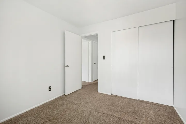 Carpeted room featuring white walls and a white door with a silver knob