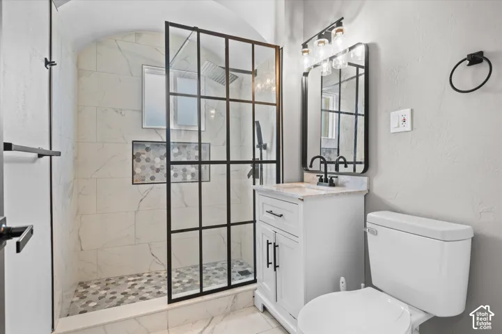 Modern bathroom featuring a walk-in shower with black-framed glass enclosure, white marble-look wall tiling, and a mosaic tiled shower floor