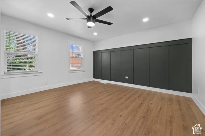 Spacious room with wood-finish flooring, recessed lighting, and a modern ceiling fan