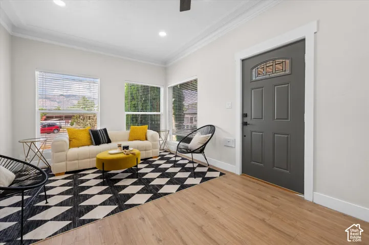 Entryway and living area featuring wood-finish flooring, a paneled entry door with decorative glass insert, multiple large windows with blinds, and recessed lighting