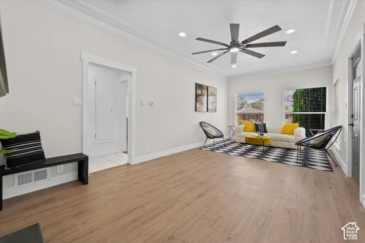 Open-concept living area featuring wood-finish flooring, a contemporary ceiling fan, recessed lighting, and crown molding