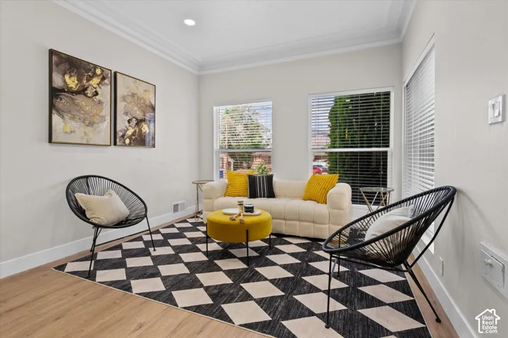 Living area featuring wood-finish flooring, white baseboards, and crown molding