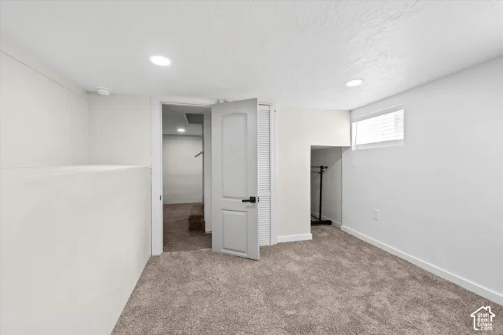 Carpeted room with a white door and a window