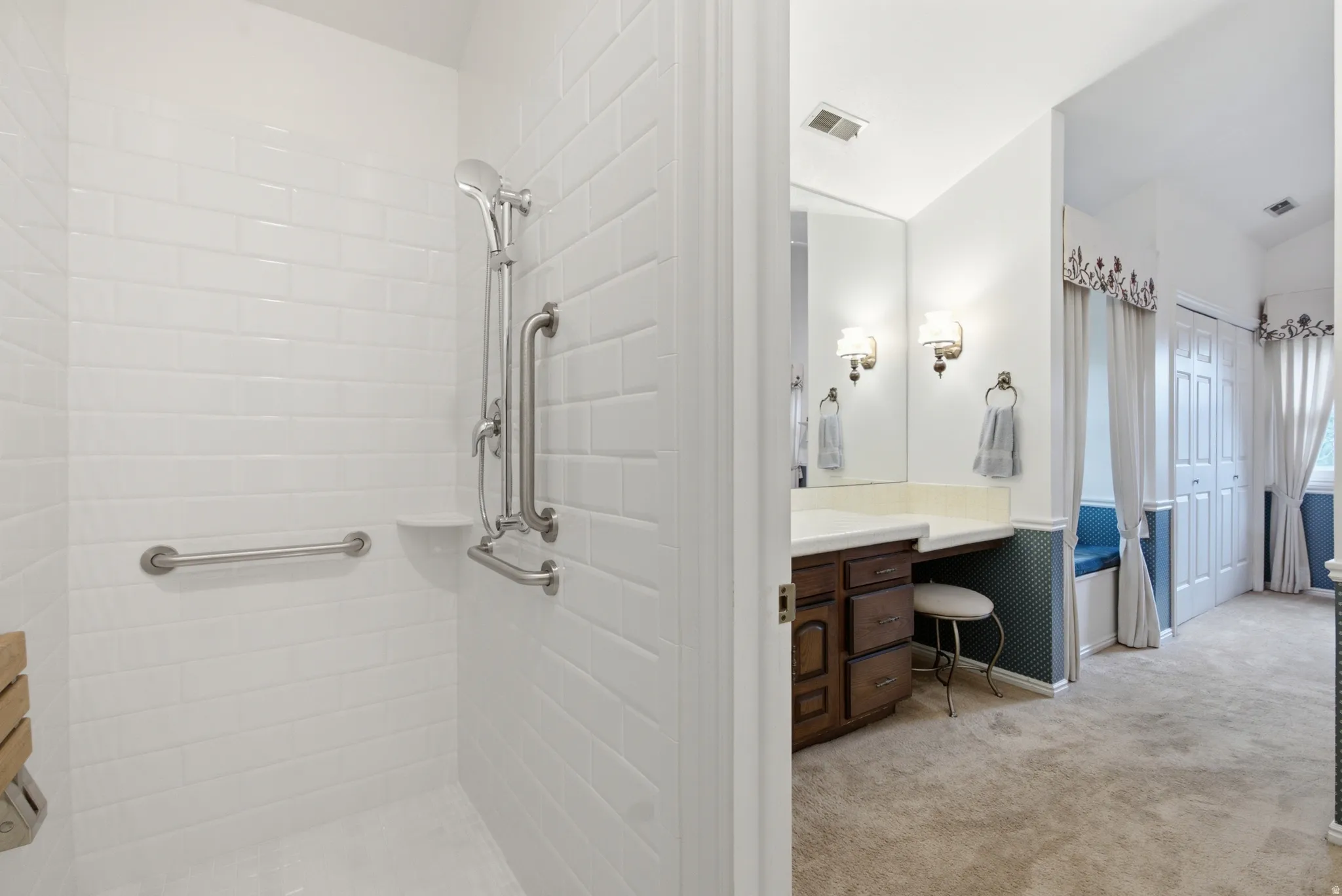 White subway tile shower with a handheld shower fixture, grab bars, and a built-in shower niche