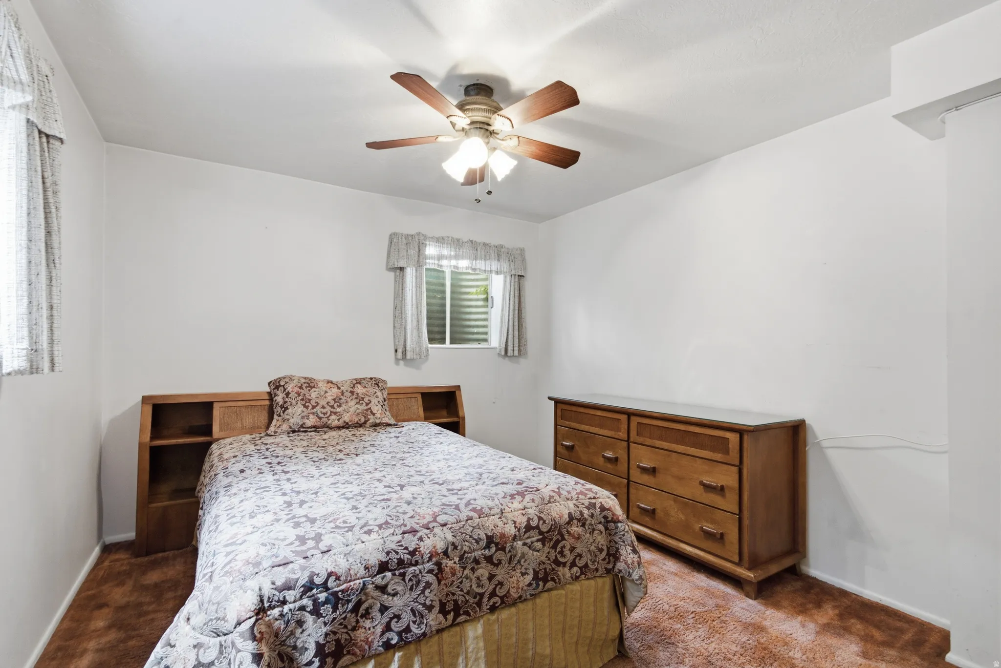 Bedroom featuring a ceiling fan with integrated lighting, a window with horizontal blinds, and neutral wall tones